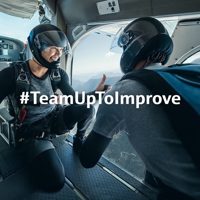 Two skydivers are ready to jump out of a flying airplane. One  shows his colleague a "thumbs up"