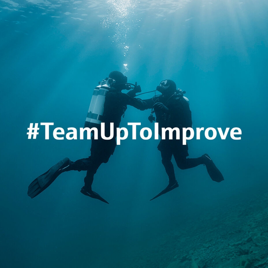 Underwater scene: a diver supports a second diver who experiences issues with the air supply.